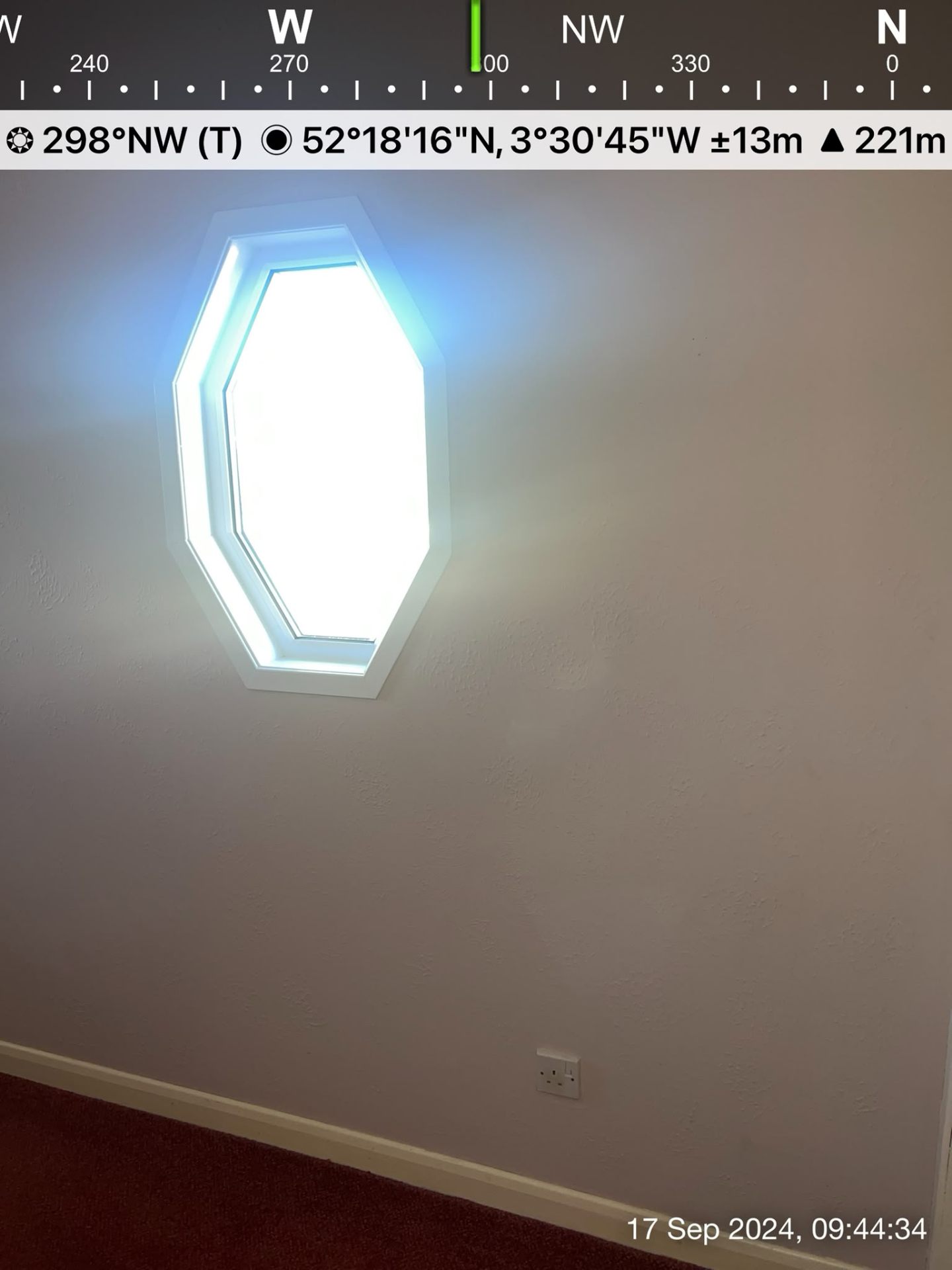 Finished interior wall with a unique hexagonal window and bright natural light coming through.