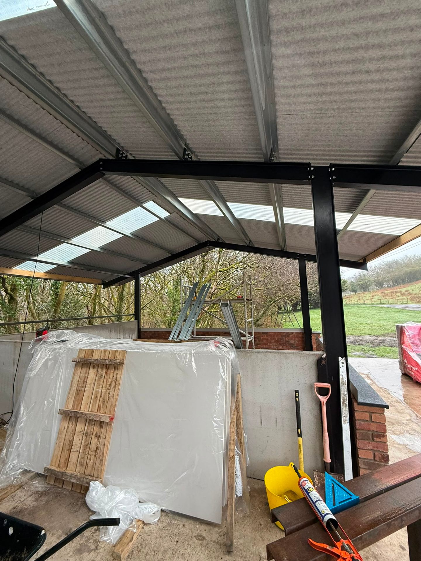 Steel frame structure of an outbuilding or extension with corrugated roofing and skylights.