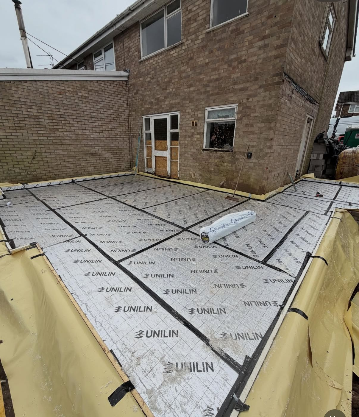 Rear extension floor build-up with taped Unilin insulation boards laid over a damp-proof membrane, ready for screed.