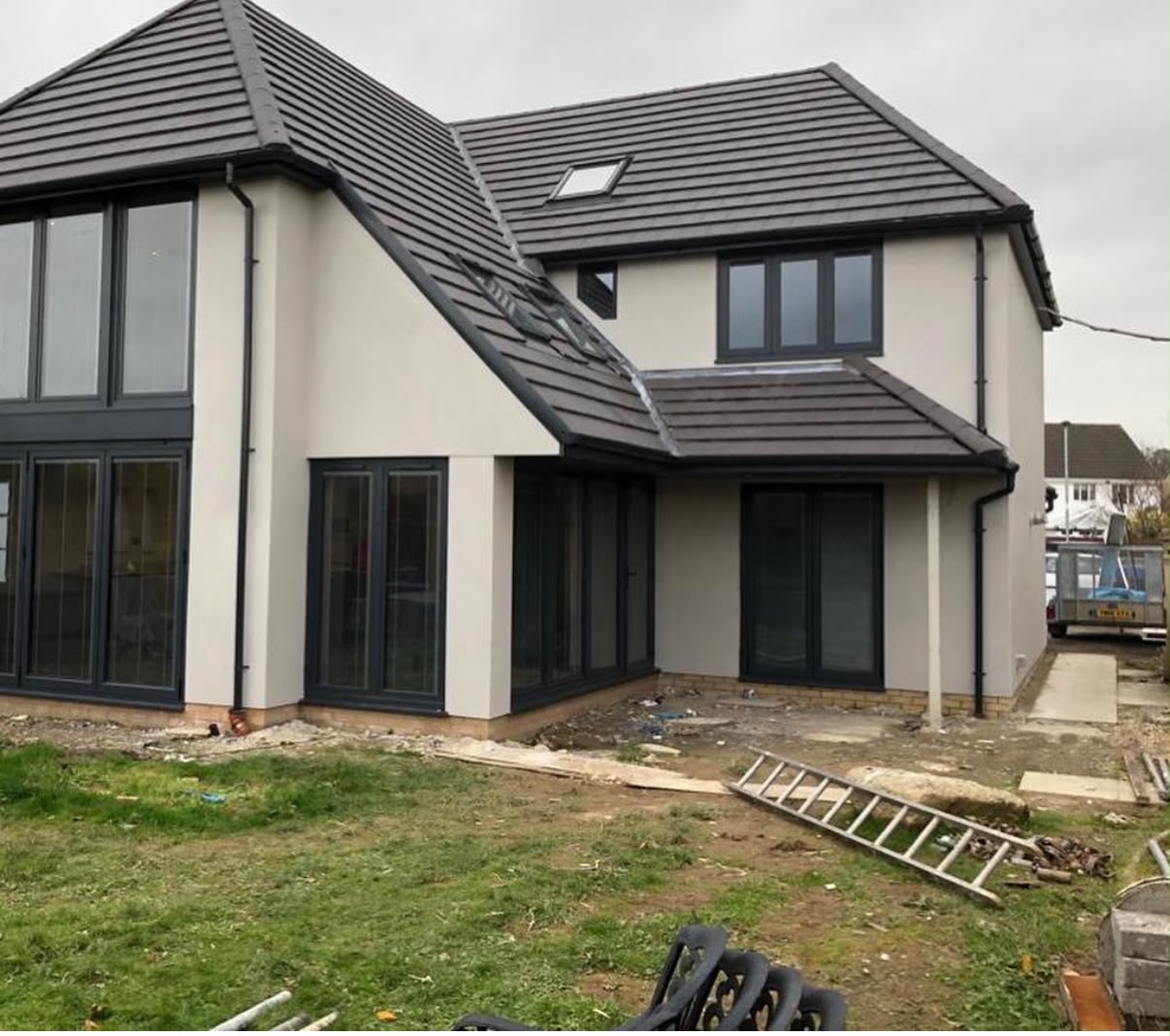 Completed modern detached family home with light-coloured render and dark grey slate roof in South Wales