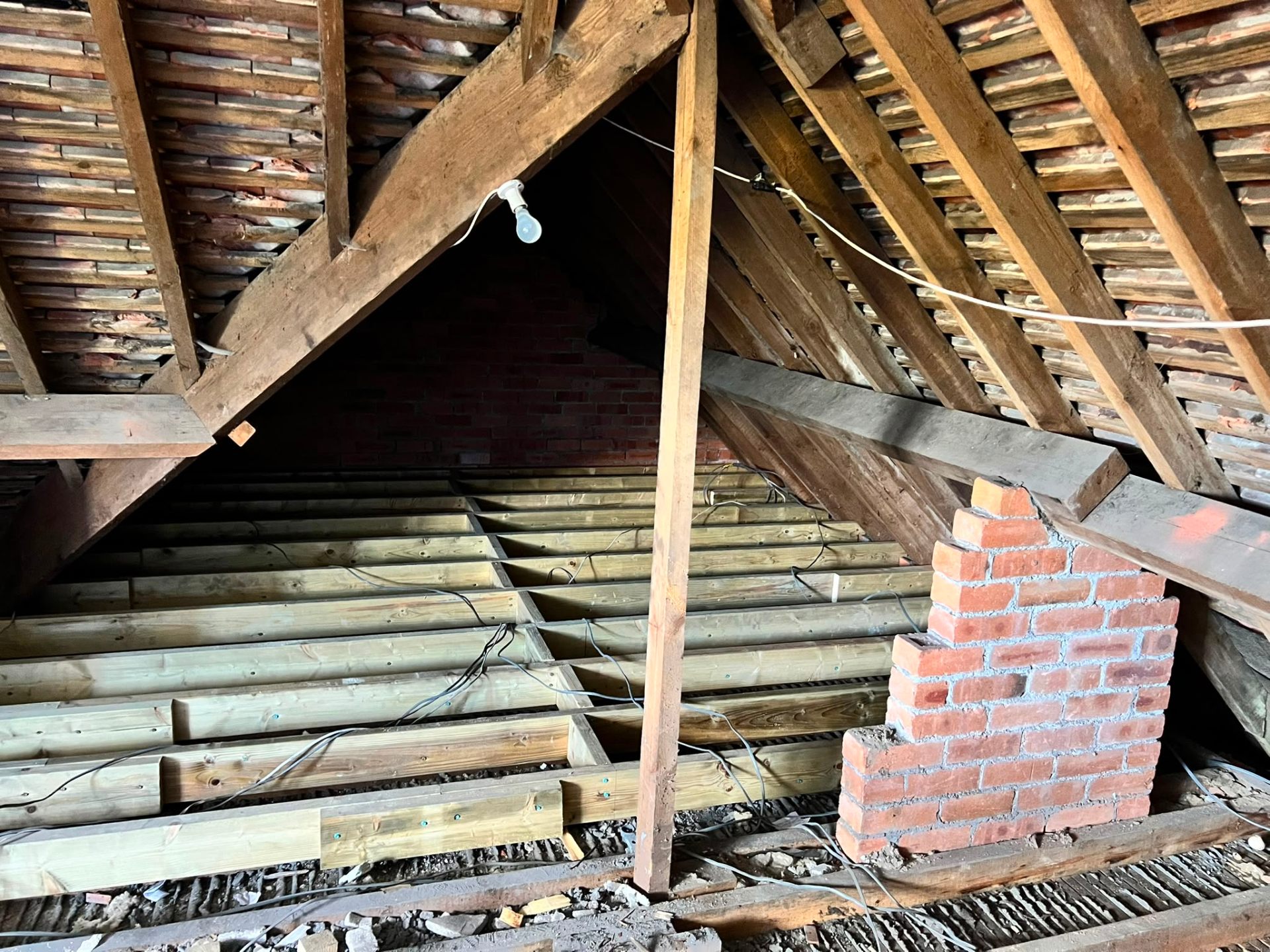 New wooden floor joists and a brick support pillar during a loft conversion project.