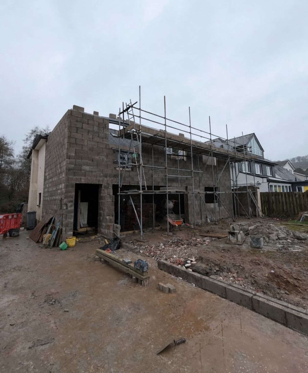 Large house extension shell in blockwork with scaffolding erected across the rear elevation during construction.