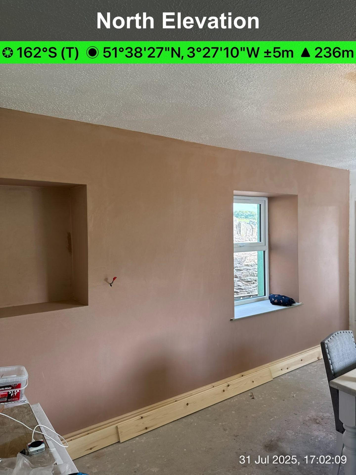 Newly plastered interior wall with a recessed shelf and a window with white frame