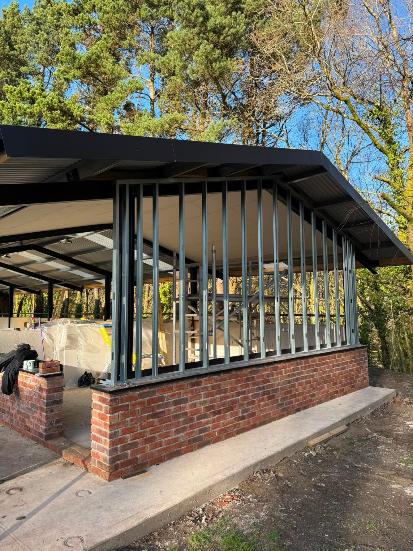 Progress shot of an extension structure featuring red brickwork and steel vertical wall framing.