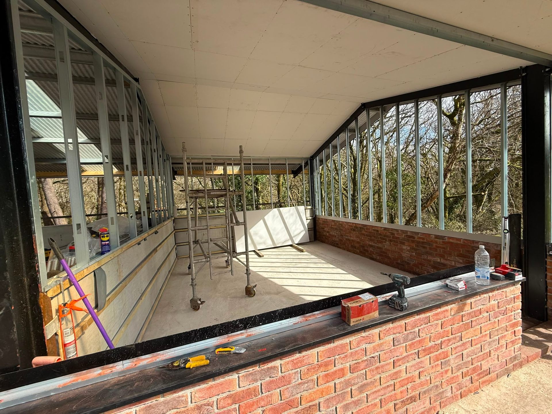 Interior view of an extension project showing brickwork and metal frame partitioning with scaffolding