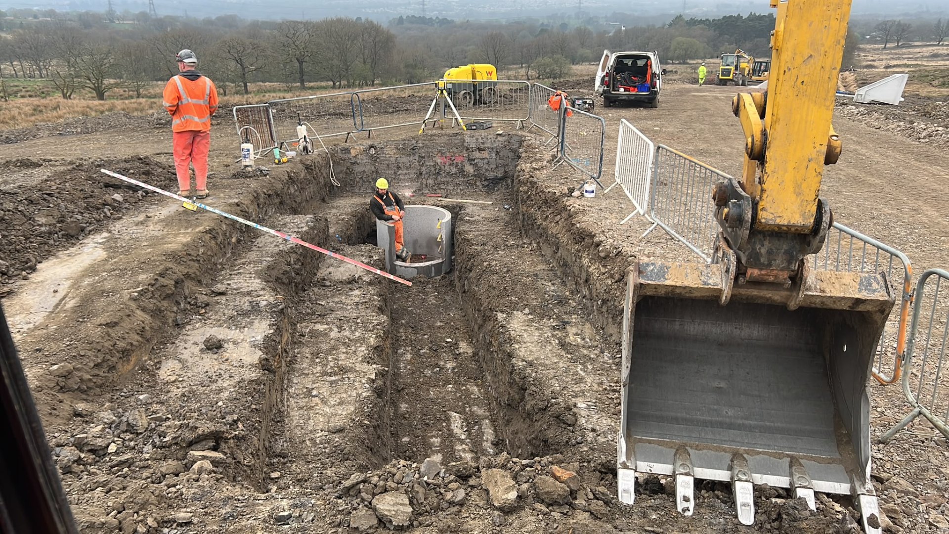 Groundwork team using excavators and diggers to install drainage systems and manholes in a field.