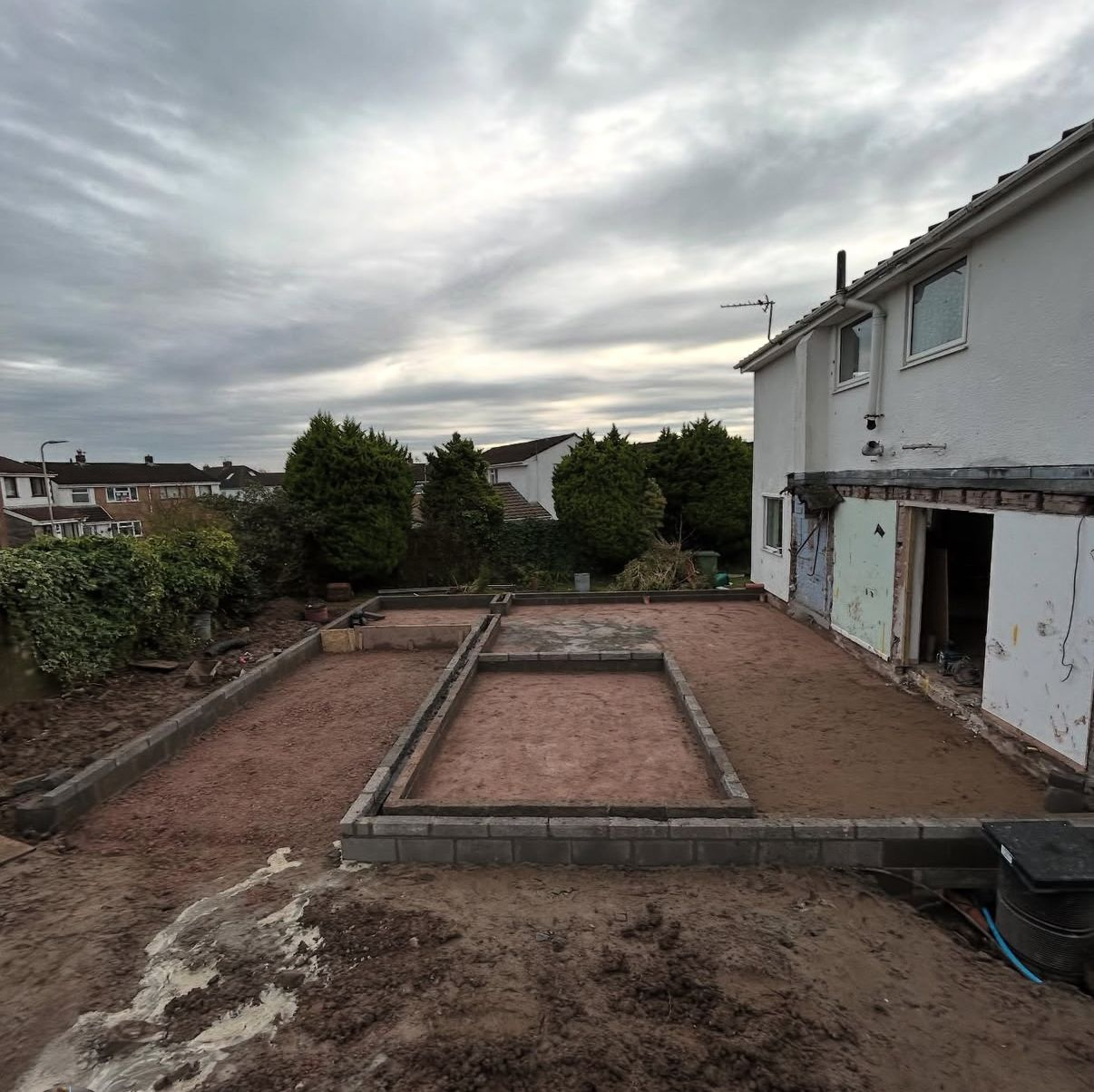 Extension groundwork and slab preparation with block perimeter walls set out across a rear garden.
