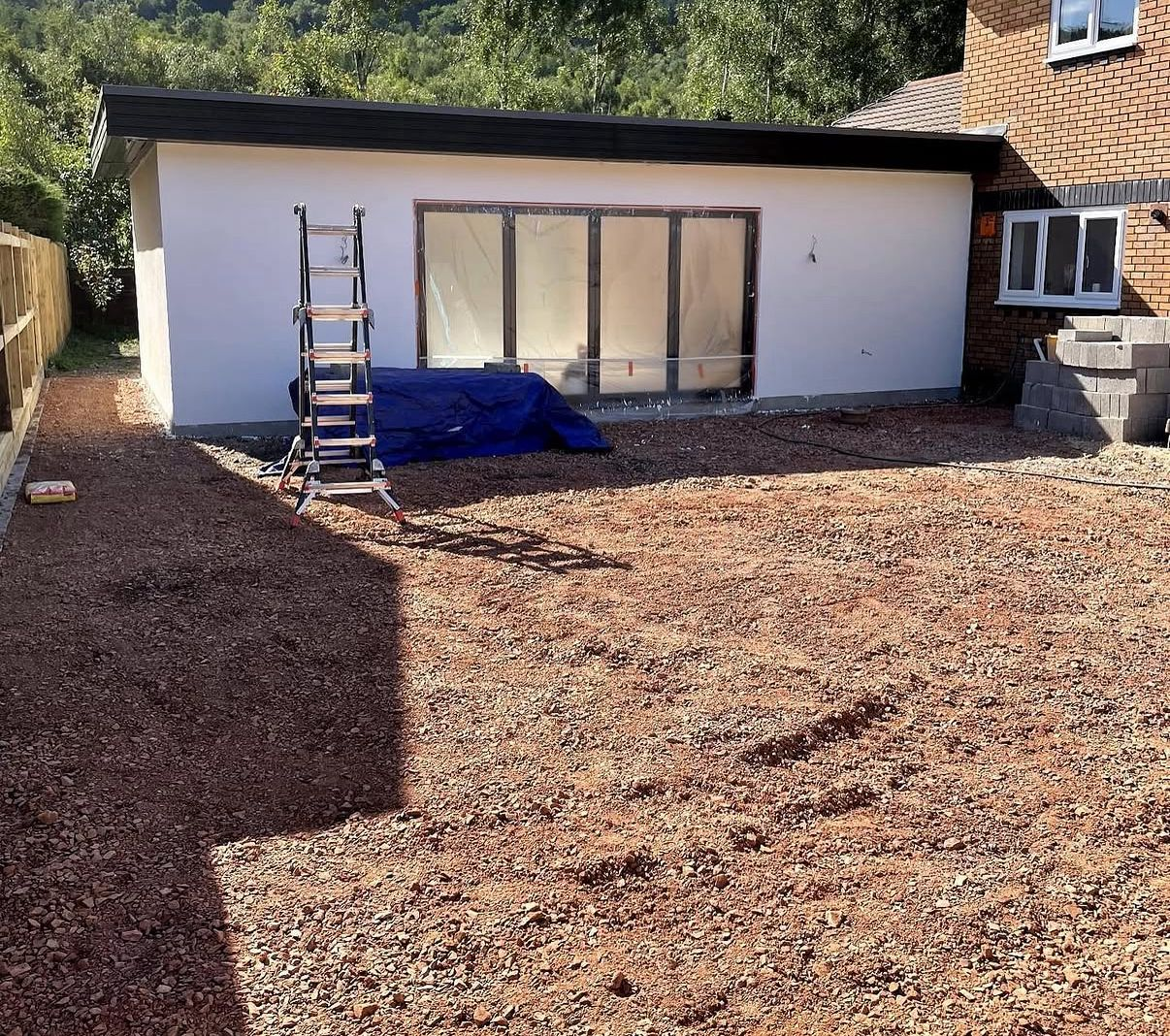 Completed rear of a modern detached new-build home with rendered walls, dark grey tiled roof, anthracite bi-fold doors and aluminium windows by LEWZ Property Development