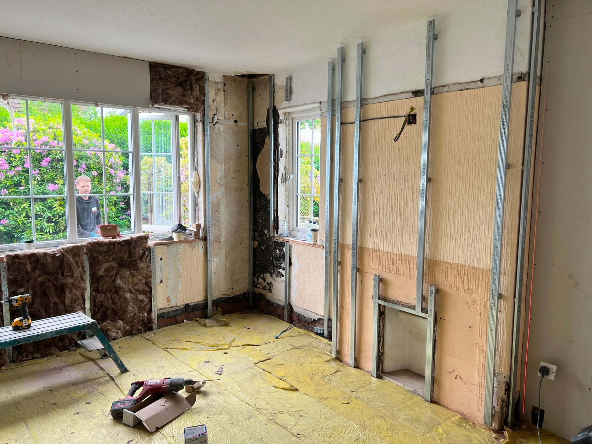 Inner wall preparation showing metal stud tracking and insulation during a residential room refurbishment.