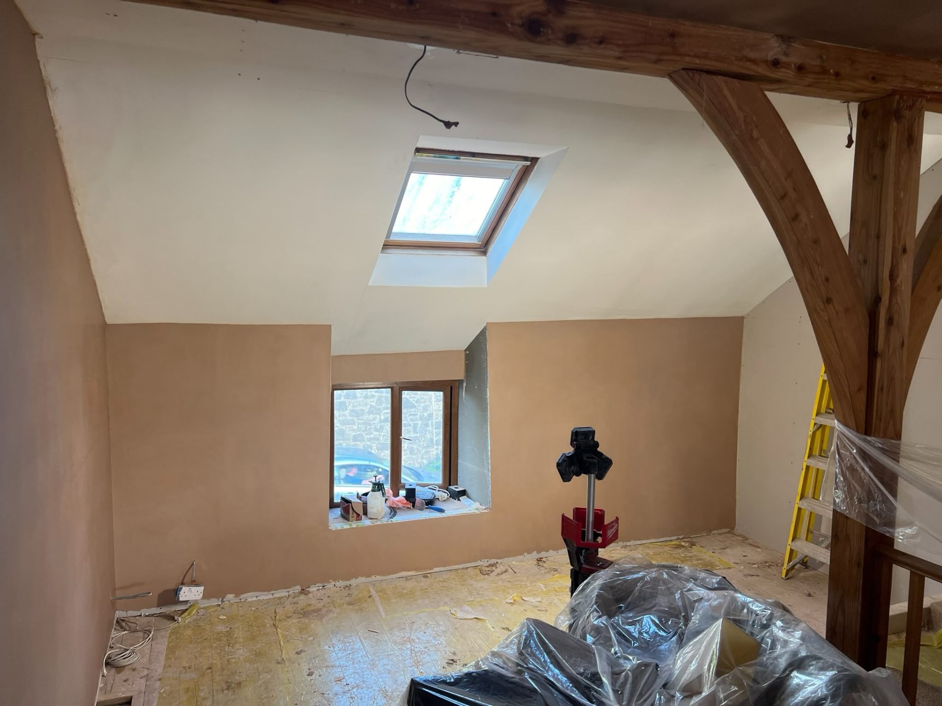 Completed attic room with character oak beams and skylight window after plastering