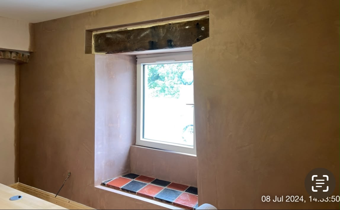 Expertly finished brown plaster around a window reveal with rustic wooden lintel by LEWZ in South Wales