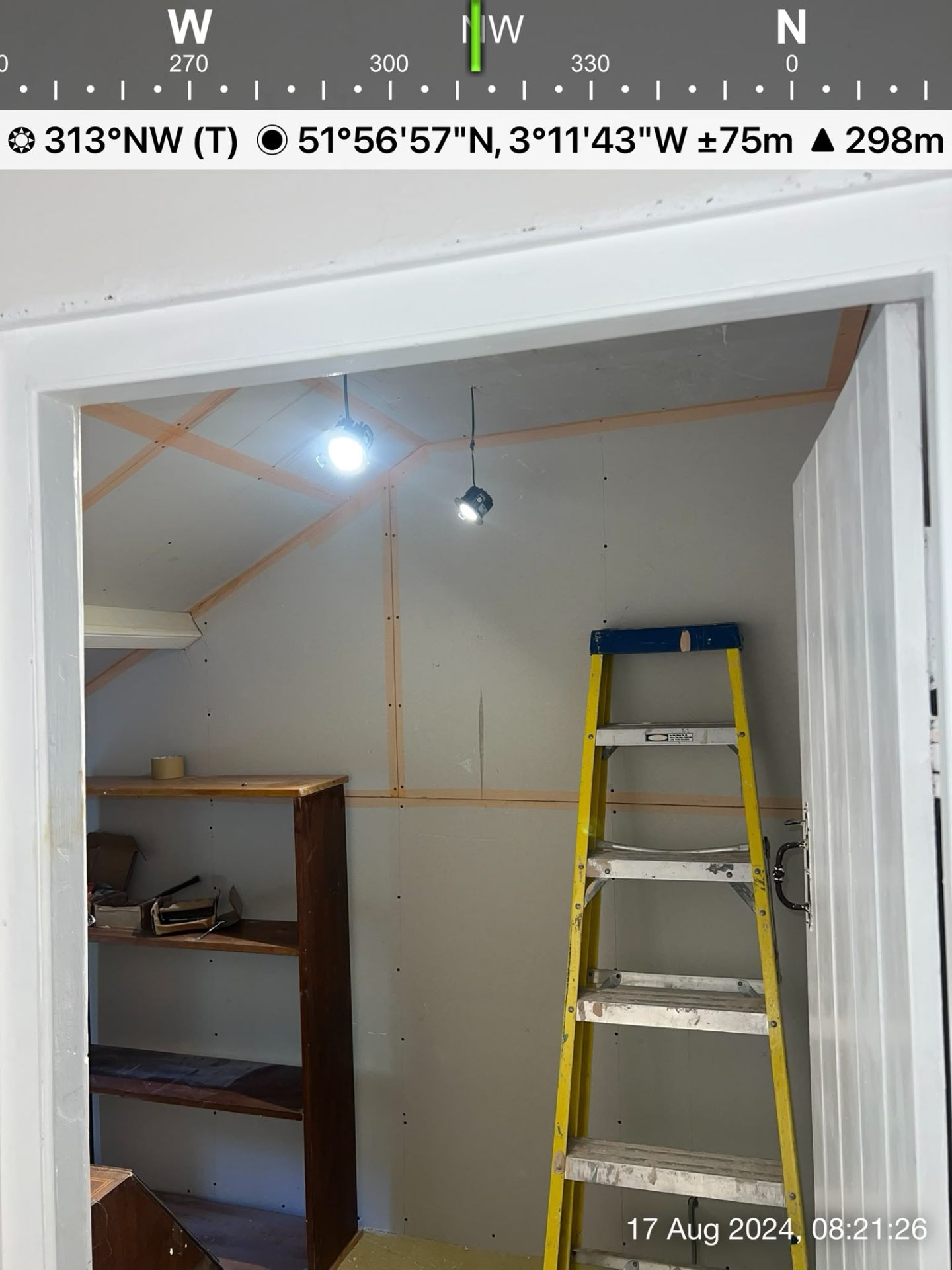 Inner room showing installed drywall boards with wooden framing visible through an open doorway.
