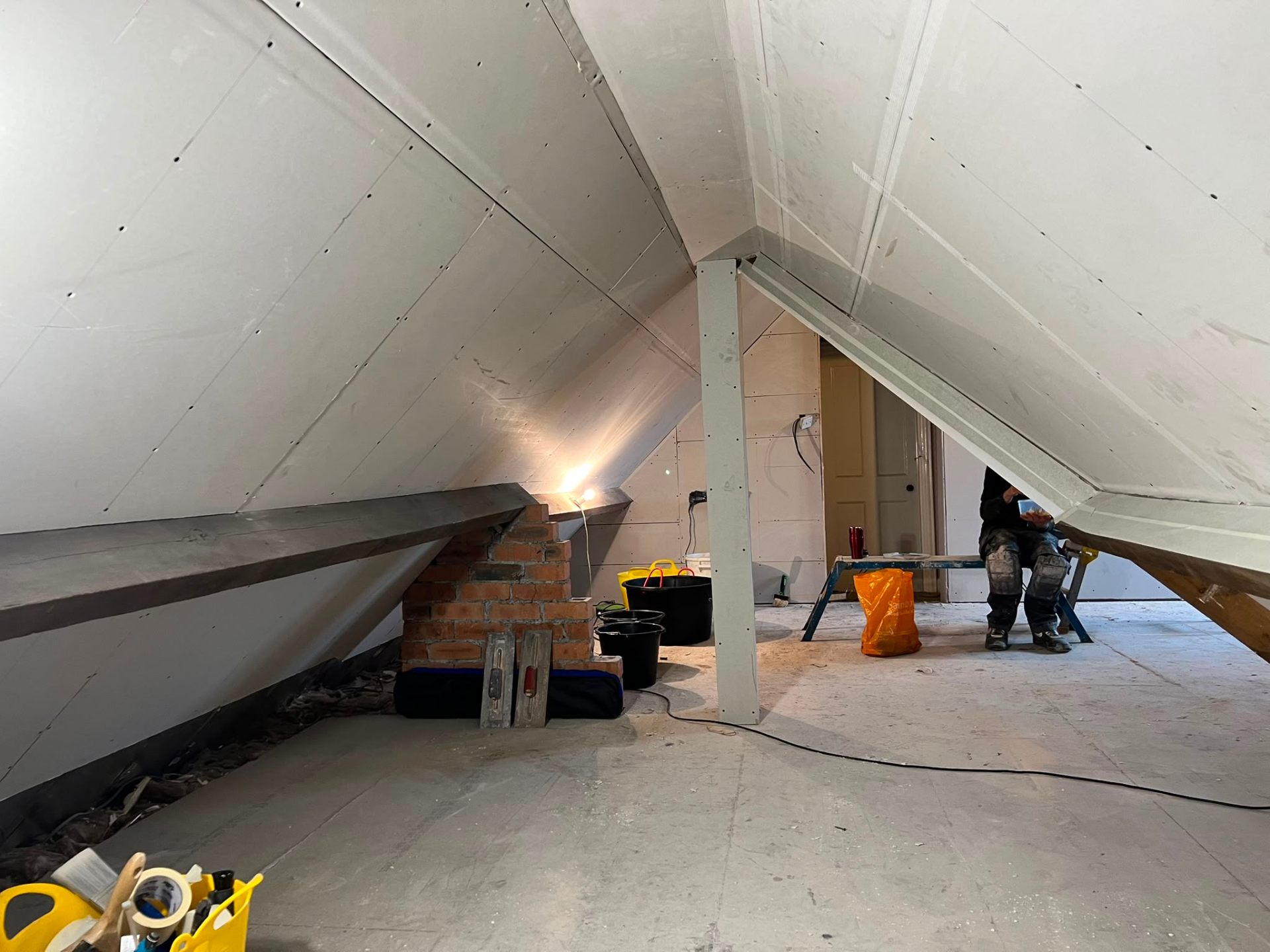 Progress shot of a loft conversion featuring plasterboard installation on angled walls and support beams.