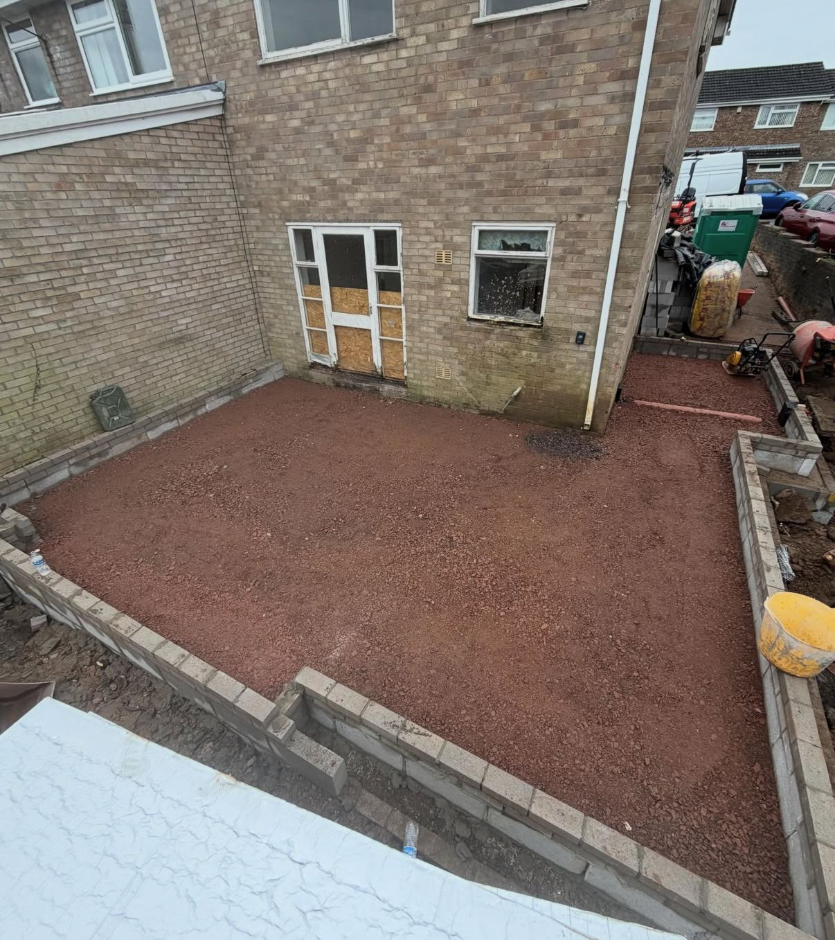 Groundworks stage of a rear extension with compacted hardcore base and surrounding blockwork ready for the next phase.