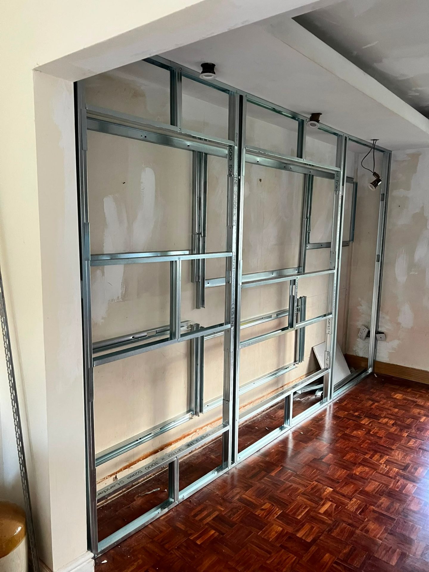 Metal stud framing for a bespoke media wall being installed in a living area.