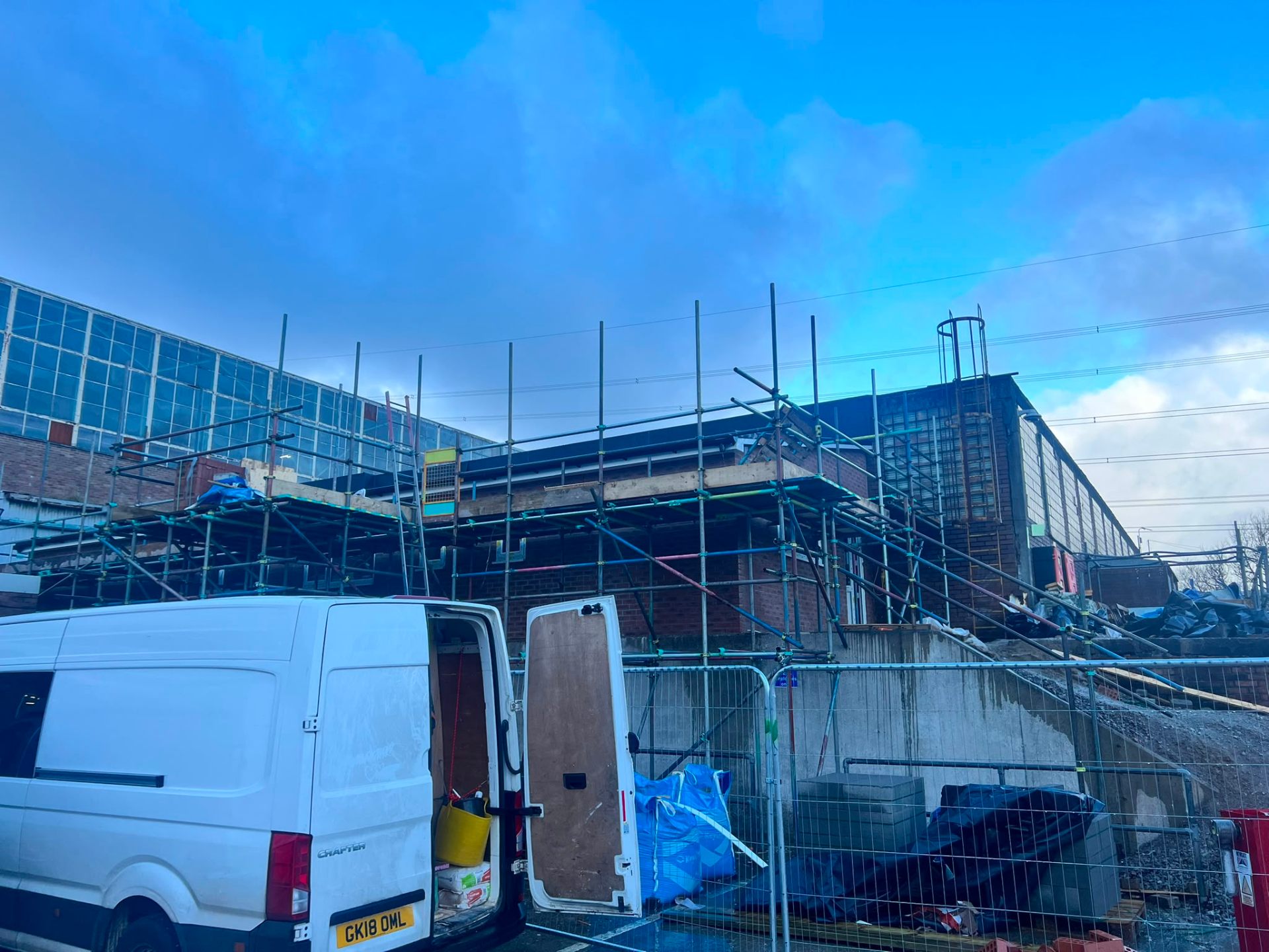 Exterior of a commercial building project with extensive scaffolding and a white contractor van.